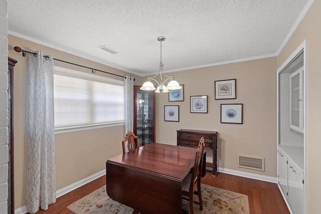 dining room featuring dark hardwood / wood-style flooring, a textured ceiling, a chandelier, and crown molding