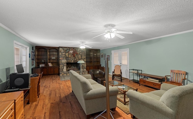 living room with a textured ceiling, a fireplace, hardwood / wood-style flooring, and crown molding