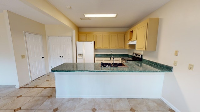 kitchen with kitchen peninsula, sink, light brown cabinets, white fridge with ice dispenser, and stainless steel electric range