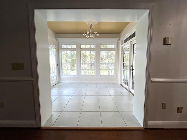 doorway to outside with a chandelier, light tile patterned floors, and a wealth of natural light