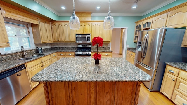 kitchen featuring a center island, sink, hanging light fixtures, appliances with stainless steel finishes, and light hardwood / wood-style floors