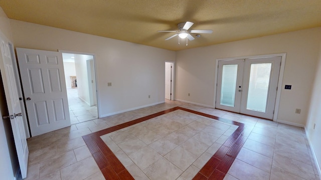 empty room featuring ceiling fan, french doors, light tile patterned flooring, and a textured ceiling