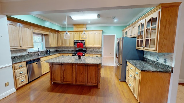 kitchen featuring a center island, dark stone countertops, light wood-type flooring, appliances with stainless steel finishes, and decorative light fixtures