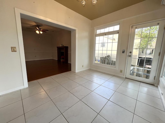 empty room featuring light tile patterned floors and ceiling fan with notable chandelier