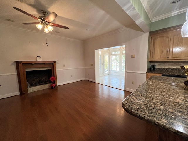 unfurnished living room featuring dark hardwood / wood-style floors, ceiling fan, ornamental molding, and sink