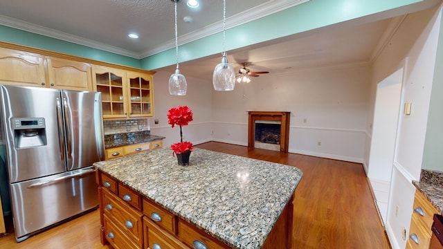 kitchen featuring a center island, stainless steel fridge with ice dispenser, backsplash, crown molding, and light hardwood / wood-style floors