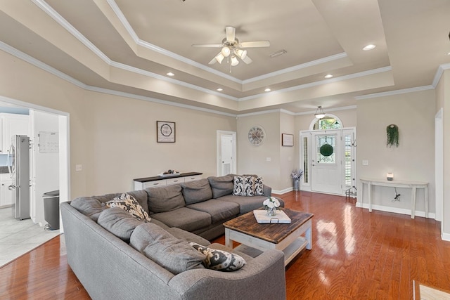 106 Lake Ln, Headland, AL 36345 - living room with a ceiling fan, a raised ceiling, light wood-style flooring, baseboards, and crown molding