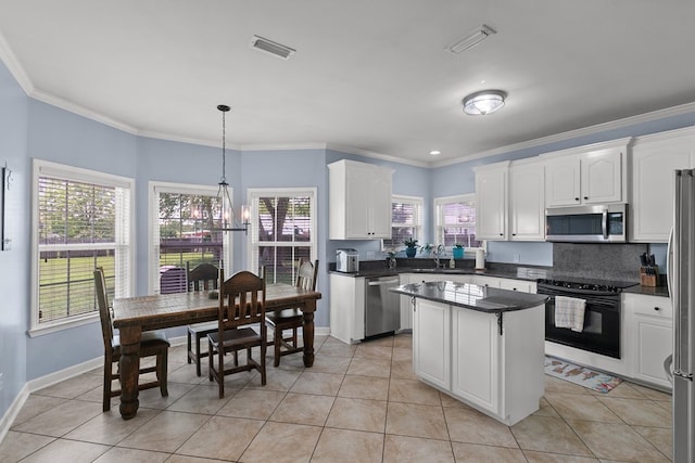 106 Lake Ln, Headland, AL 36345 - kitchen featuring appliances with stainless steel finishes, dark countertops, white cabinets, a center island, and crown molding