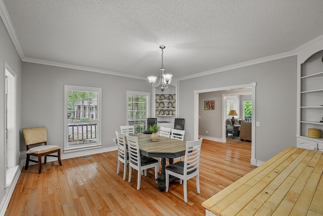408 Shakespeare Dr, Dothan, AL 36303 - dining space featuring a chandelier, crown molding, a textured ceiling, light wood-style floors, and plenty of natural light
