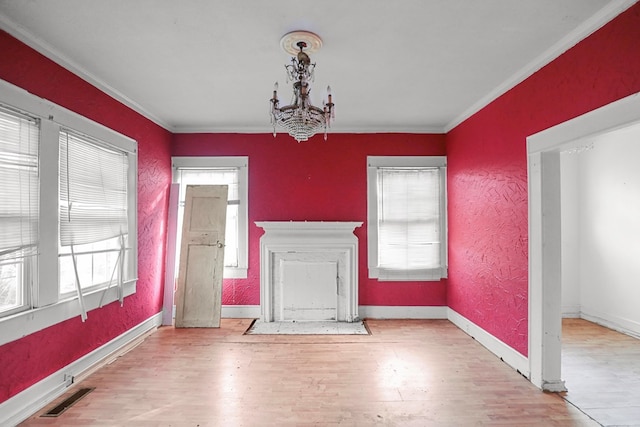 unfurnished dining area featuring an inviting chandelier, a healthy amount of sunlight, ornamental molding, and light hardwood / wood-style flooring