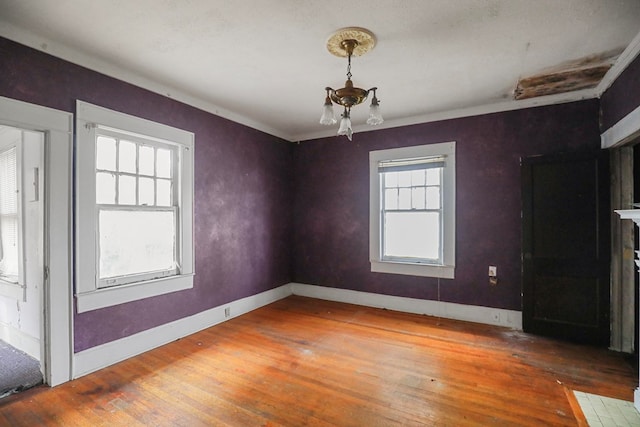 unfurnished dining area featuring ornamental molding, wood-type flooring, and a notable chandelier