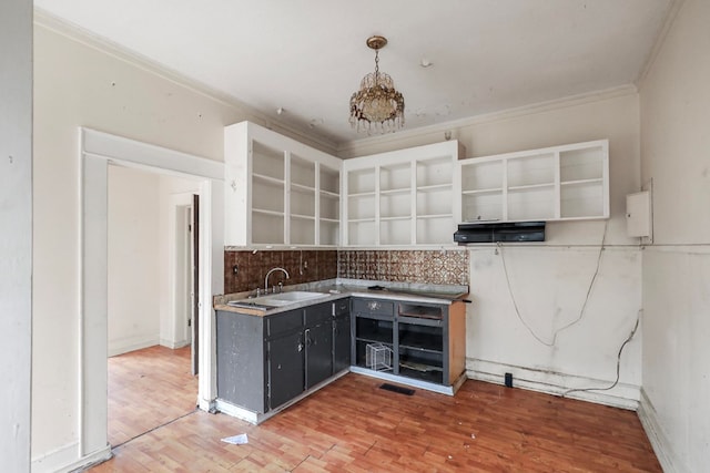 kitchen with hanging light fixtures, crown molding, wood-type flooring, and sink