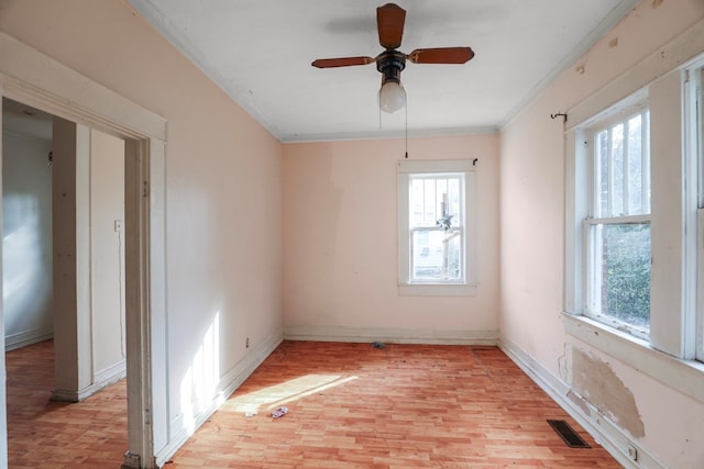 empty room featuring crown molding, ceiling fan, light hardwood / wood-style floors, and a wealth of natural light