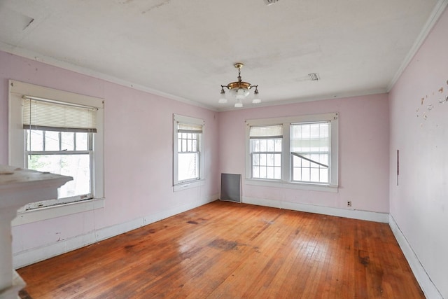 spare room with a notable chandelier, crown molding, and light hardwood / wood-style flooring