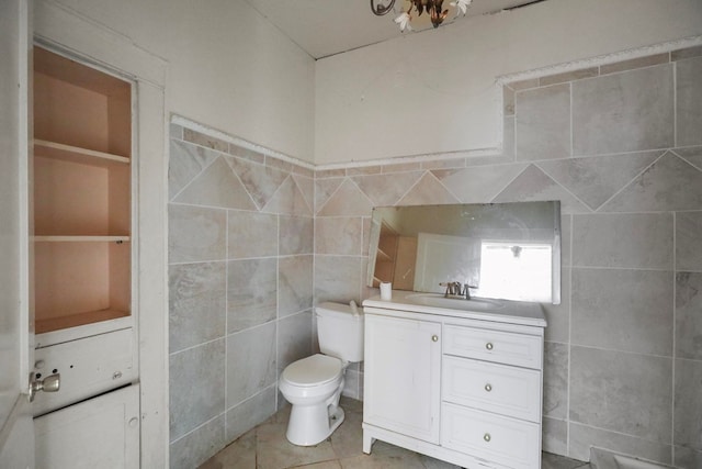 bathroom with tile patterned flooring, vanity, tile walls, and toilet