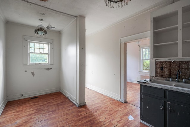 kitchen with hardwood / wood-style floors, ornamental molding, sink, and pendant lighting