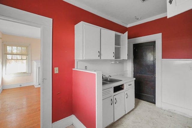 kitchen featuring white cabinetry, sink, and ornamental molding