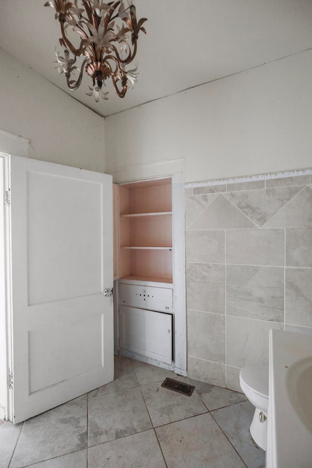 bathroom with tile patterned floors, toilet, and tile walls