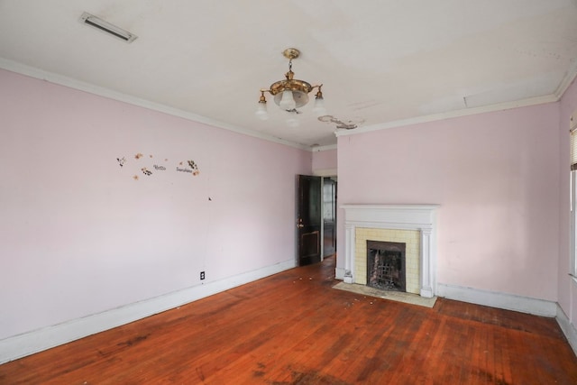 unfurnished living room with ornamental molding, dark hardwood / wood-style flooring, a brick fireplace, and a notable chandelier