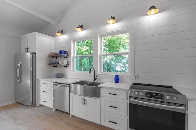 kitchen featuring wood walls, lofted ceiling with beams, sink, light wood-type flooring, and stainless steel appliances