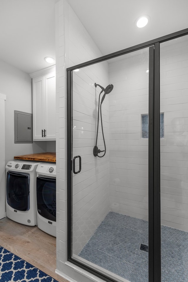 bathroom featuring hardwood / wood-style floors, electric panel, independent washer and dryer, and a shower with shower door