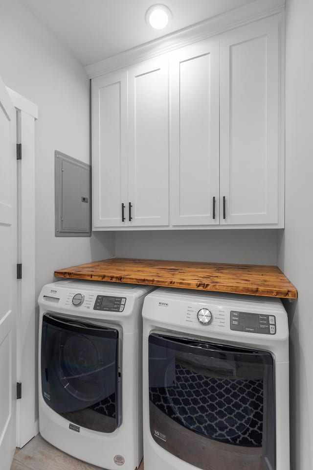 laundry room featuring light hardwood / wood-style floors, cabinets, independent washer and dryer, and electric panel