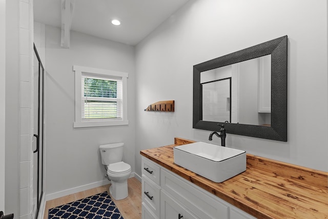 bathroom featuring toilet, an enclosed shower, wood-type flooring, and vanity