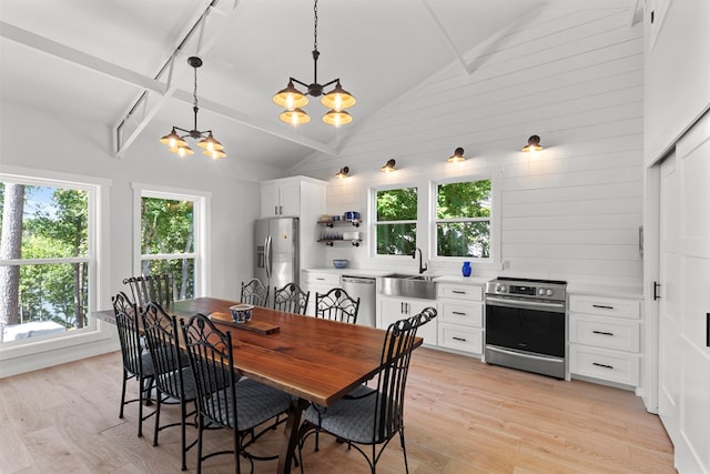 dining room featuring wood walls, high vaulted ceiling, sink, light hardwood / wood-style floors, and a chandelier