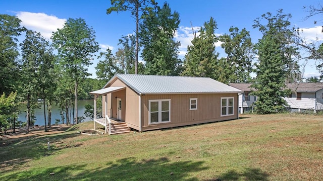 rear view of property with an outbuilding, a water view, and a lawn