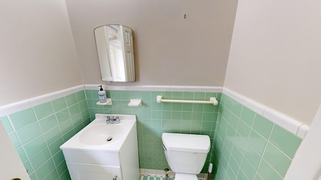 bathroom featuring vanity, toilet, and tile walls