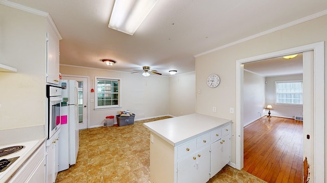 kitchen with white appliances, light hardwood / wood-style floors, white cabinetry, and a wealth of natural light