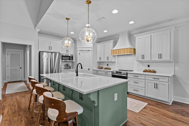 246 Suggs Rd, Dothan, AL 36345 - kitchen featuring appliances with stainless steel finishes, custom range hood, a breakfast bar, an island with sink, and white cabinetry