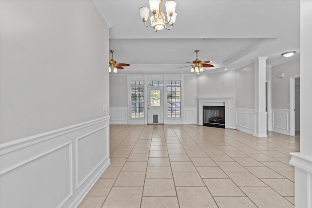 unfurnished living room featuring ceiling fan with notable chandelier, a tray ceiling, light tile patterned floors, and crown molding