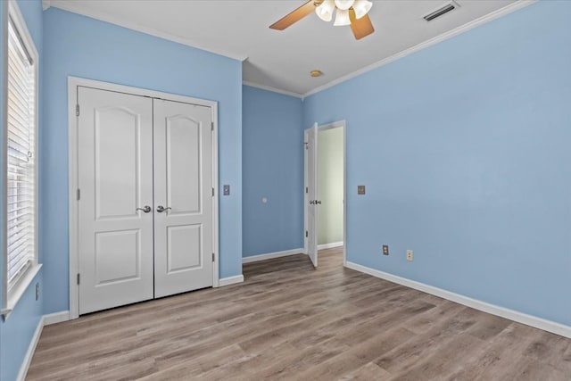 unfurnished bedroom featuring a closet, ceiling fan, crown molding, and light wood-type flooring