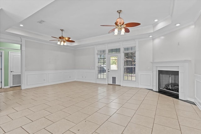 unfurnished living room with light tile patterned floors, ceiling fan, ornamental molding, and a tray ceiling