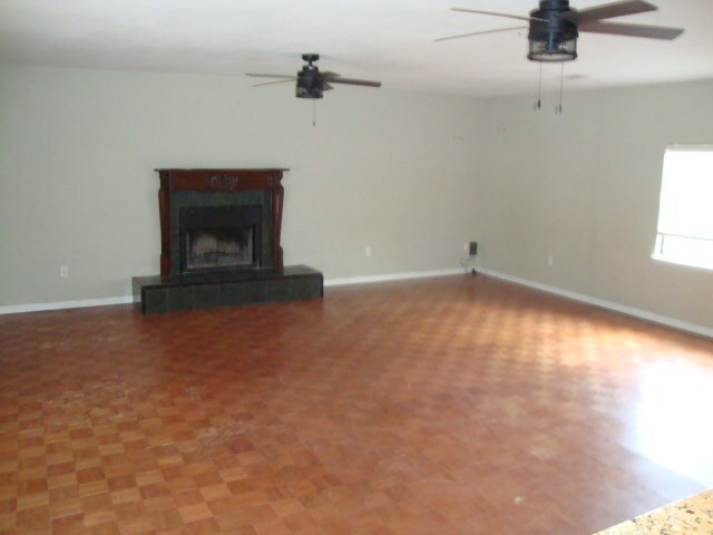 801 Early Walden Rd, Headland, AL 36345 - unfurnished living room featuring ceiling fan, baseboards, and a tile fireplace