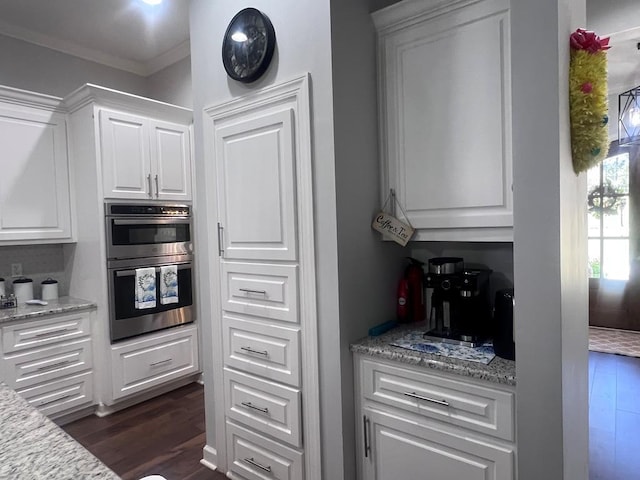 kitchen with dark wood finished floors, white cabinets, light stone countertops, and stainless steel double oven