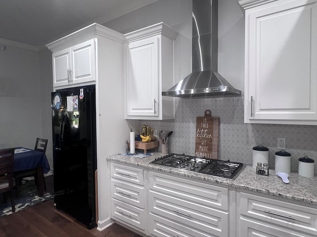 kitchen with black fridge, stainless steel gas stovetop, wall chimney exhaust hood, decorative backsplash, and dark wood-style flooring