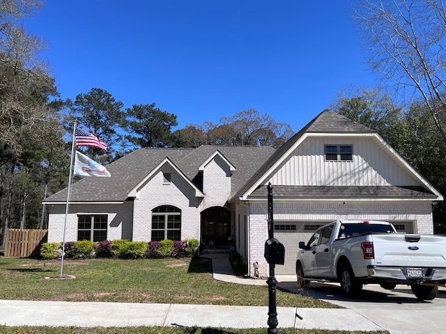 view of front facade with driveway, fence, board and batten siding, a front yard, and brick siding