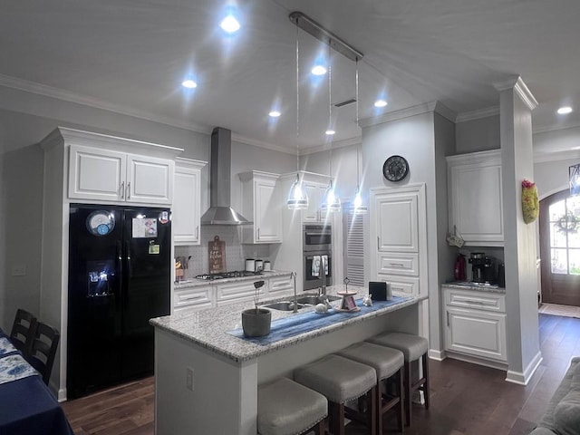 kitchen featuring a sink, wall chimney range hood, white cabinetry, and stainless steel appliances