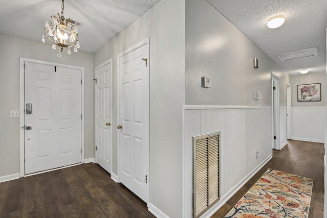 hall featuring a textured ceiling, a chandelier, and dark hardwood / wood-style floors