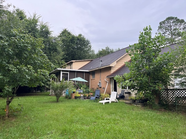 132 Ozark Rd, Abbeville, AL 36310 - back of house with a sunroom, a yard, brick siding, and a shingled roof