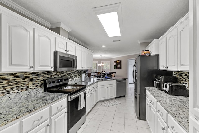 208 Willow Oaks Dr, Headland, AL 36345 - kitchen featuring light tile patterned floors, a peninsula, white cabinets, appliances with stainless steel finishes, and a sink
