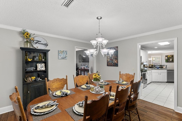 208 Willow Oaks Dr, Headland, AL 36345 - dining space with light wood finished floors, an inviting chandelier, ornamental molding, and visible vents