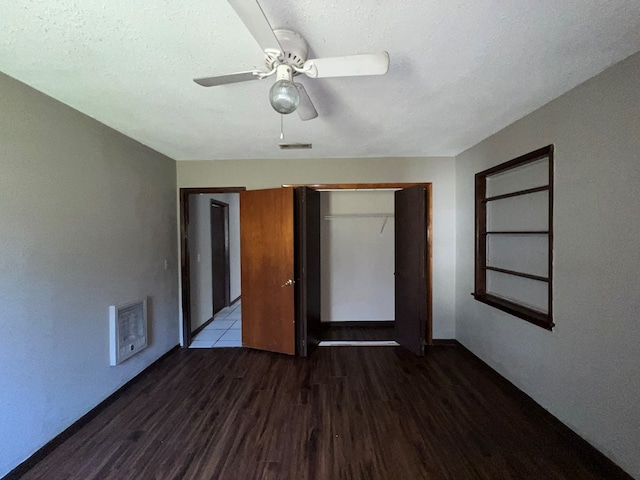 unfurnished bedroom featuring visible vents, heating unit, a textured ceiling, wood finished floors, and a closet