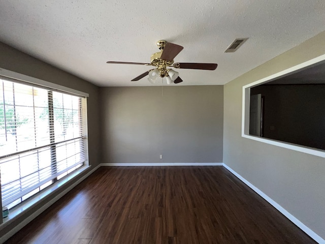 empty room with visible vents, baseboards, dark wood-style flooring, and a textured ceiling