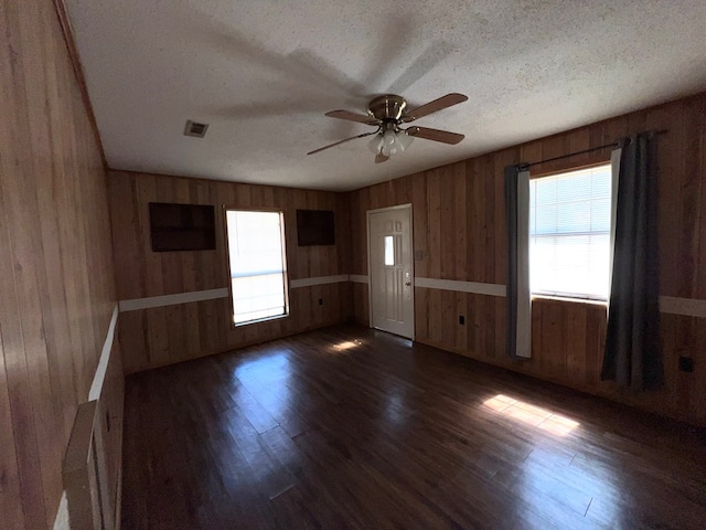 unfurnished room with visible vents, a textured ceiling, dark wood finished floors, and a ceiling fan