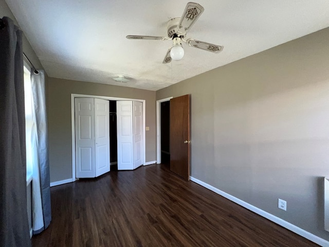 unfurnished bedroom with a closet, dark wood-type flooring, and baseboards