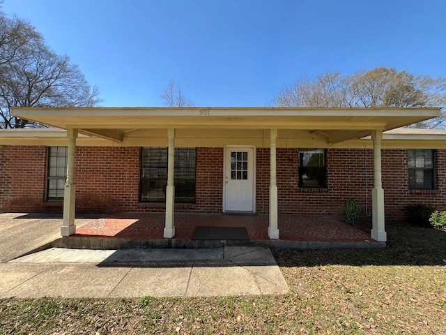 entrance to property featuring a porch and brick siding