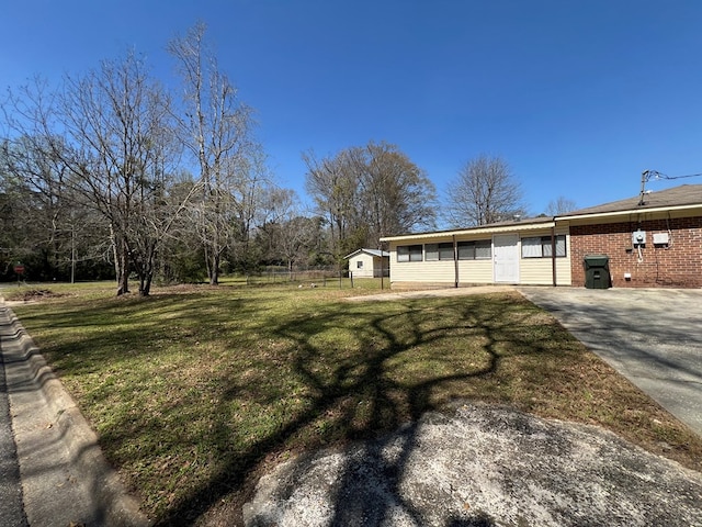 view of yard featuring concrete driveway and fence